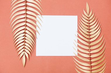 Pembe arka planda altın palmiye dalları ve kare tahta.