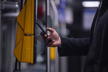 Adam cep telefonundaki uygulamayı kullanarak terminalden toplu taşıma bileti alıyor.