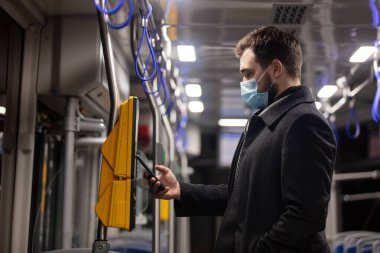 Adam cep telefonundaki uygulamayı kullanarak terminalden toplu taşıma bileti alıyor.
