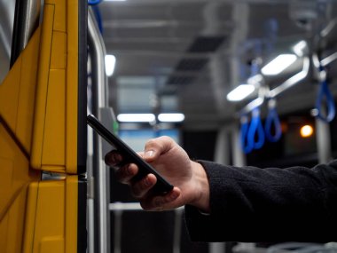 Adam cep telefonundaki uygulamayı kullanarak terminalden toplu taşıma bileti alıyor.