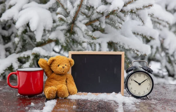 暴风雪中木制桌子上装有闹钟的玩具熊和黑板 — 图库照片