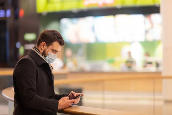 Facet Masce Płaszczu Używa Telefonu Komórkowego Centrum Handlowym Czasie Pandemii — Zdjęcie stockowe