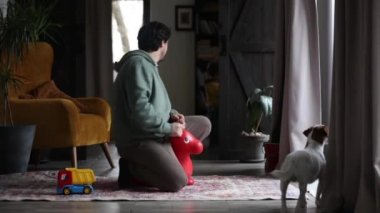 Bir adam oyuncak bir ata biner ve onunla atlamaya çalışır.