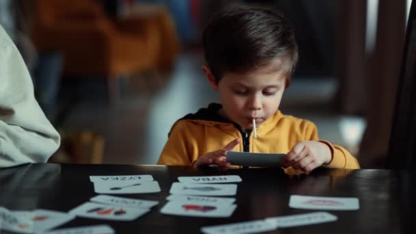 在美国律师协会的治疗计划下 小男孩在家里的饭桌上从卡片中学习单词 — 图库视频影像