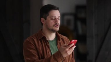 Gülümseyen adam evde telefonla konuşuyor.