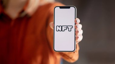Wroclaw, Polonya - 20 Mart 2021: ekranda NFT logosu olan iPhone 12 'yi tutan kadın