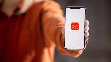 Wroclaw, Polonya - 20 Mart 2021: Ekranda AliExpress mağaza logosu olan iPhone 12 'yi tutan kadın