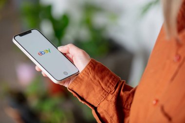 Wroclaw, Polonya - 20 Mart 2021: eBay logosu olan iPhone 12 'yi elinde tutan kadın