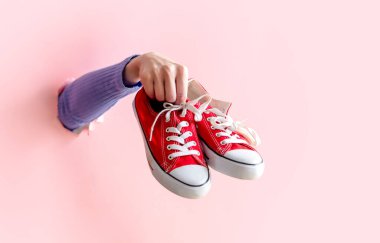 Kadın eli pembe arka planda kırmızı jelibon tutuyor..