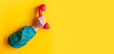 Kadın el ele tutuşması klasik kırmızı cep telefonu sarı arka planda.