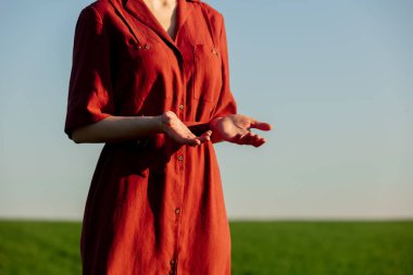 Baharda yeşil bir tarlada kırmızı elbiseli kadının gövdesine bakın.