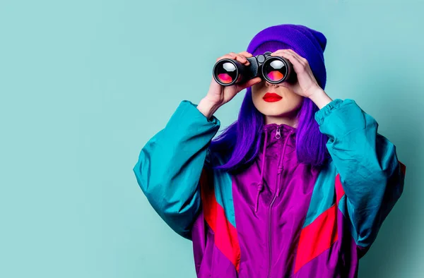 青の背景に双眼鏡を使用した紫の髪と80年代のトラックスーツを持つスタイリッシュな白い女の子 — ストック写真