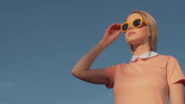 Stile Donna Abito Rosa Con Occhiali Gialli Sfondo Cielo Blu — Video Stock