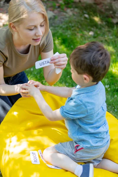 mom teaches to pronounce words using the Doman technique for an autistic child in the yard