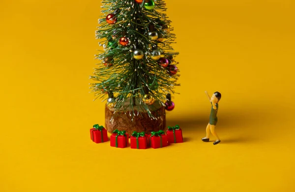 身材矮小的男孩站在黄色背景的红色圣诞灯罩附近 — 图库照片