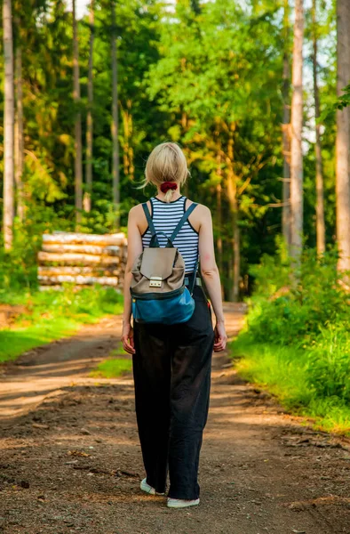 Blond hair woman in pants waking in a forest