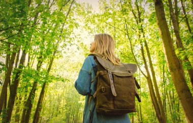 Young woman with backpack in a mixed forest Beskidy in Poland in spring time.