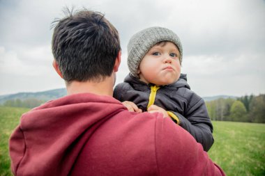 Father and son hugging on vacation on spring time meadow in mountains