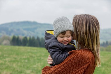 Motherr and son hugging on vacation on spring time meadow in mountains
