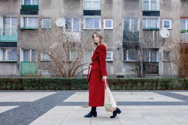 Kırmızı ceketli stil kadın ve net çanta alışverişten sonra eve uyanma. Doğu Avrupa 
