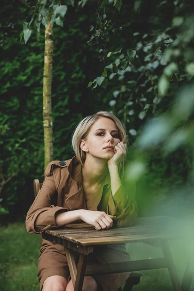 Beautiful Woman Coat Blond Hair Sits Wooden Table Garden Trees — Stock Photo, Image