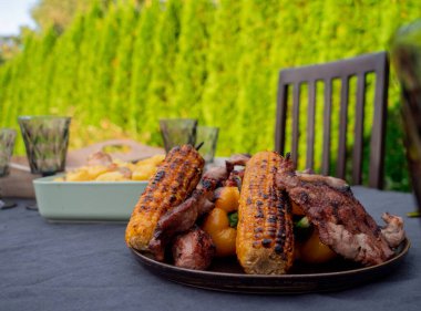 Bir masada ızgara mısır ve domuz eti. 