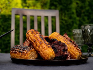 Bir masada ızgara mısır ve domuz eti. 