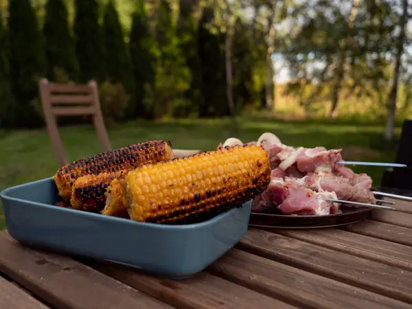 Bir masada ızgara mısır ve domuz eti. 