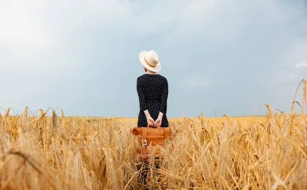 帽子の女性と黒のドレスにスーツケース付き小麦畑 — ストック写真