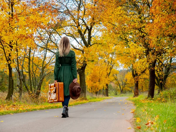 Kobieta Zielonym Płaszczu Walizką Wiejskiej Drodze Okresie Jesiennym — Zdjęcie stockowe