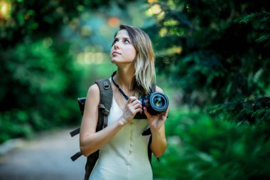 Parkta fotoğraf makinesi ve sırt çantası olan genç bir kız.