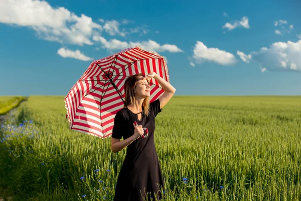 緑の小麦畑に赤い傘を差した黒いドレスの少女 — ストック写真