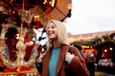 Dresden, Almanya 'daki Noel pazarında atlıkarınca yakınında sarışın bir kadın.