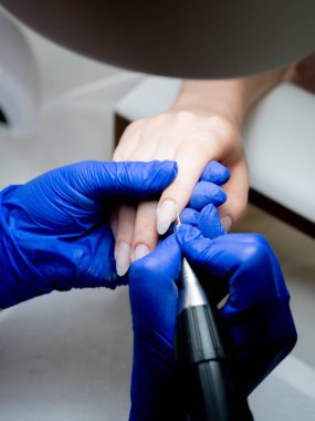 Manikür ustası çivileri makineyle temizliyor.