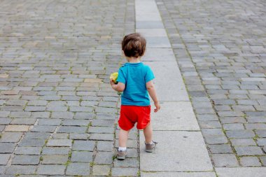 Eski şehirde kaldırımda yürüyen küçük yürümeye başlayan çocuk