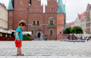 Eski şehirde kaldırımda yürüyen küçük yürümeye başlayan çocuk