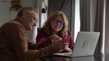 Evde dizüstü bilgisayarla internette sörf yapan iki yaşlı insan. 4K video 