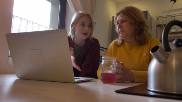 家のキッチンでラップトップでインターネットをサーフィンする女性との義母 — ストック動画