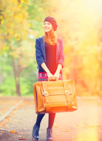 Roodharige meisje met koffer in herfst buiten. — Stockfoto