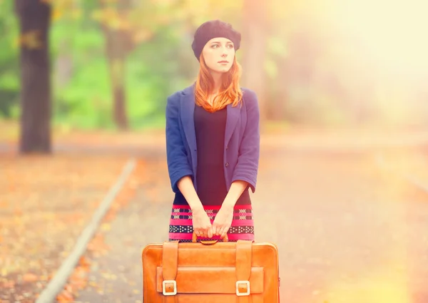 Redhead girl with suitcase at autumn outdoor. — Stock Photo, Image