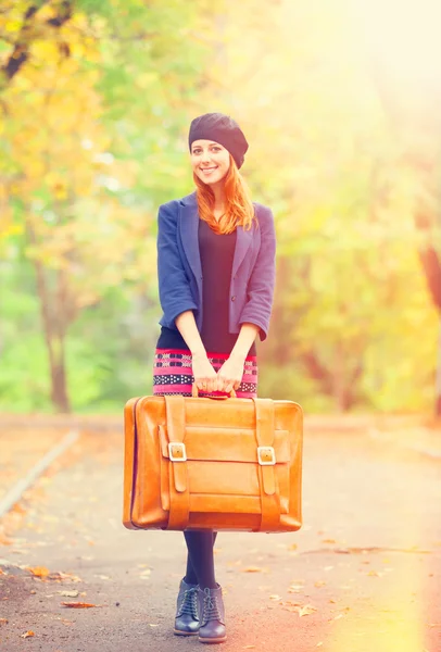 Рыжая девушка с чемоданом на осеннем открытом воздухе . — стоковое фото