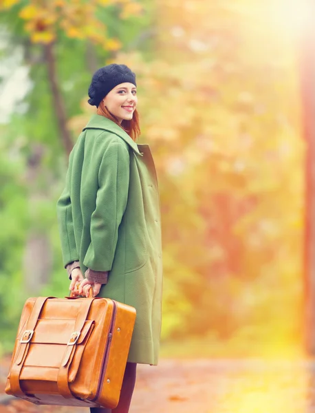 Roodharige meisje met koffer in herfst buiten. — Stockfoto