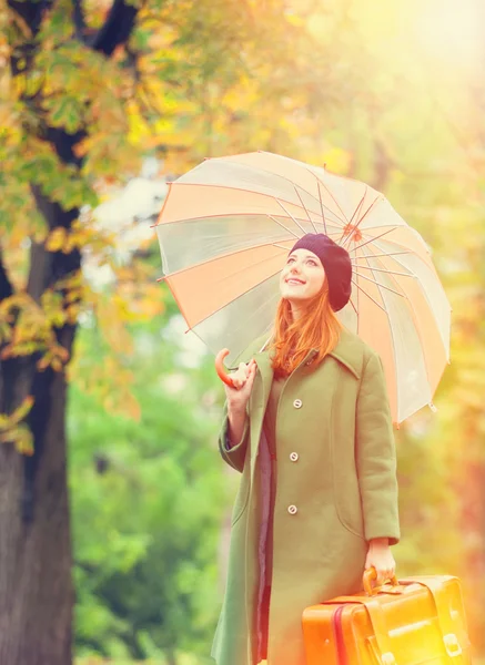 Rothaarige Mädchen mit Koffer im Herbst im Freien. — Stockfoto