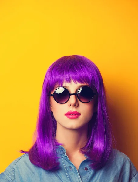 Belle fille aux cheveux violets dans les lunettes de soleil sur fond jaune — Photo