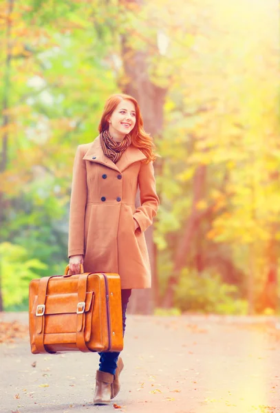 Pelirroja con maleta en otoño al aire libre — Foto de Stock