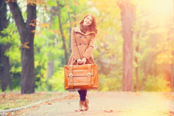 Redhead girl with suitcase at autumn outdoor — Stock Photo, Image