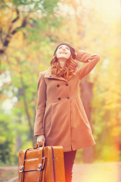 Roodharige meisje met koffer in herfst buiten — Stockfoto