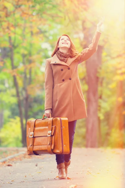 Rusovláska dívka s kufrem na podzim venkovní — Stock fotografie