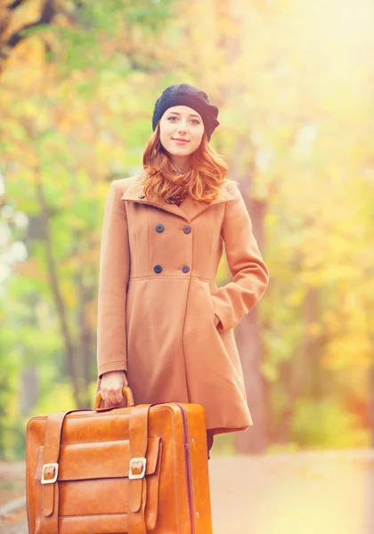 Pelirroja con maleta en otoño al aire libre — Foto de Stock