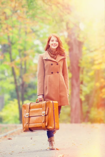 Rödhårig tjej med resväska på hösten utomhus — Stockfoto